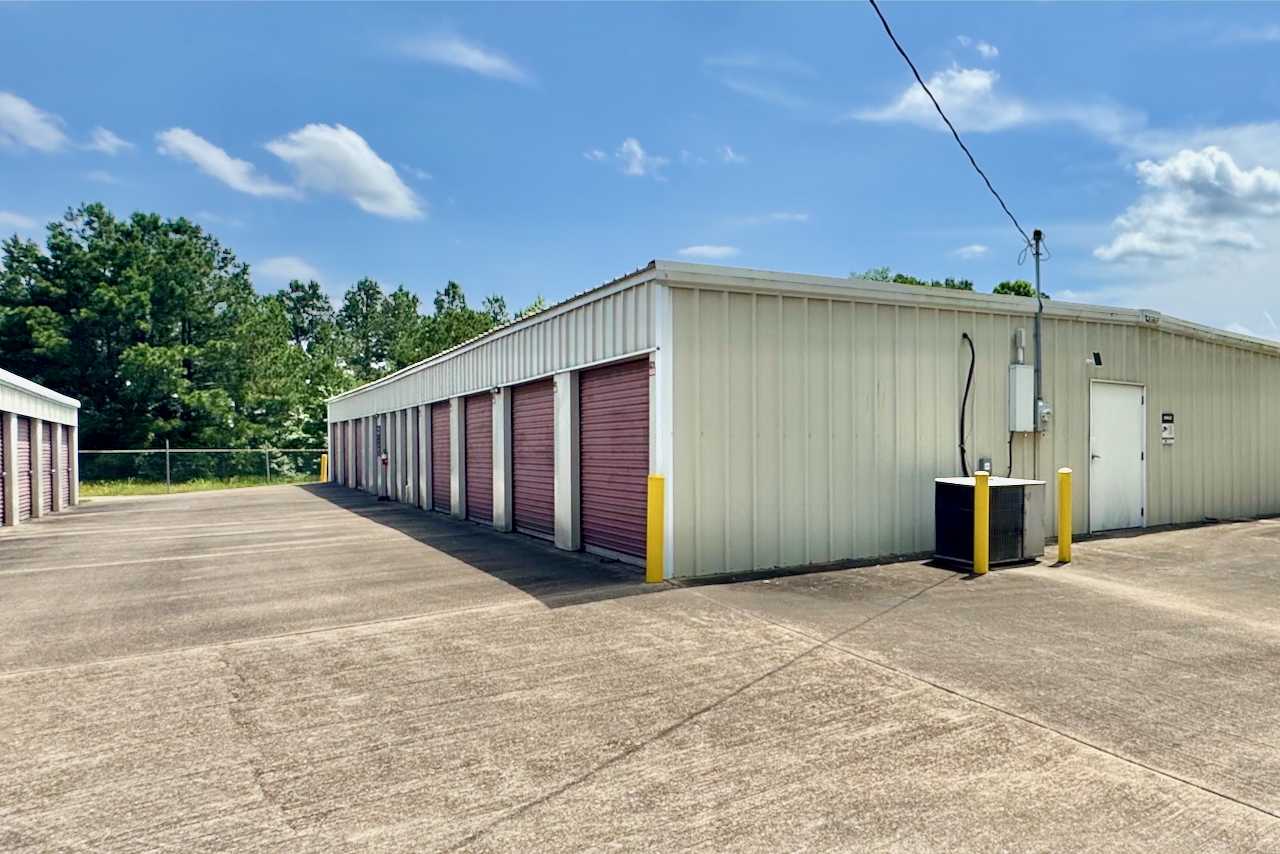 Multiple exterior drive-up unit doors at Storage Depot, fenced for safety and suited for business inventory storage
